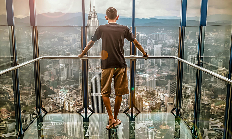 Man standing in glass lift over large city