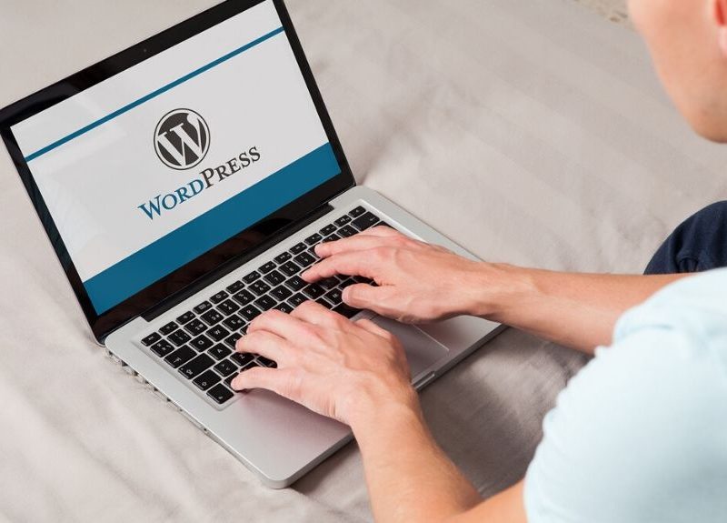 Wordpress brand logo on computer screen. Man typing on the keyboard. WordPress is a free and open-source blogging tool and a content management system (CMS).